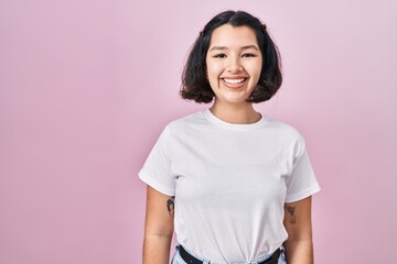 Fototapeta premium Young hispanic woman wearing casual white t shirt over pink background with a happy and cool smile on face. lucky person.