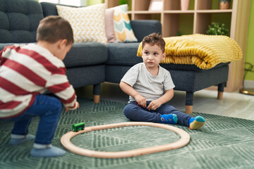 Two kids playing with train toy sitting on floor at home