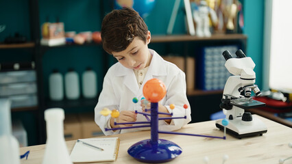 Adorable hispanic boy astronomer student make planetary work at laboratory classroom