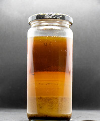 Layers of cooking Fat Oil and Grease in a glass jar. On a black background