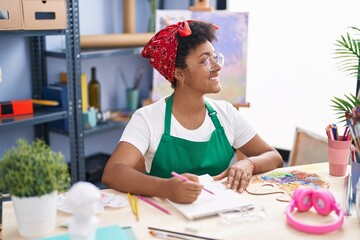 African american woman artist smiling confident drawing on notebook at art studio