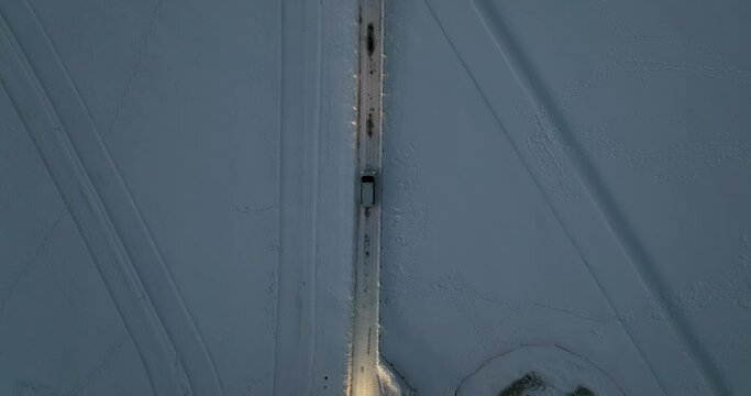 Aerial tracking shot of a white van on a snowy road Swiss winter 4K