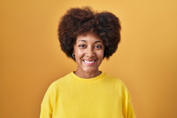 Obraz na płótnie Canvas Young african american woman standing over yellow background with a happy and cool smile on face. lucky person.