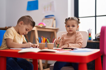 Two kids preschool students sitting on table drawing on paper at kindergarten