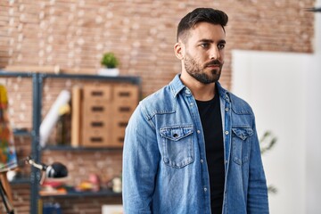 Young hispanic man standing with relaxed expression at art studio