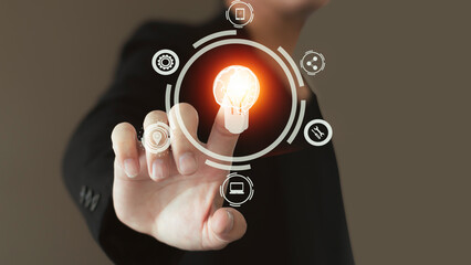 Touch of male hand pressing on creative virtual light bulb hologram with a human brain on background, concept and brainstorming, learning