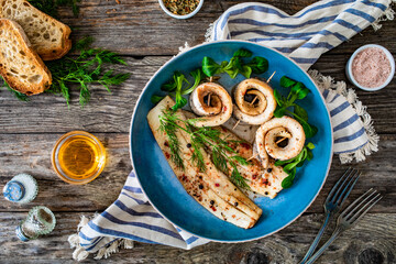 Marinated herring fillets with dill on wooden table
