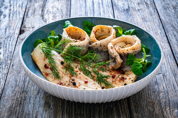 Marinated herring fillets with dill on wooden table
