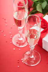 Valentines Day or Romantic dinner concept. Romantic table setting, silverware, wine glasses, gift box, roses and symbol of love red heart on red background. Romantic Dinner Valentines Day concept.