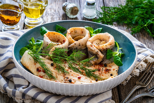 Marinated herring fillets with dill on wooden table
