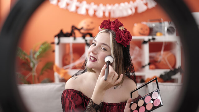 Young blonde woman wearing katrina costume recording makeup video at home