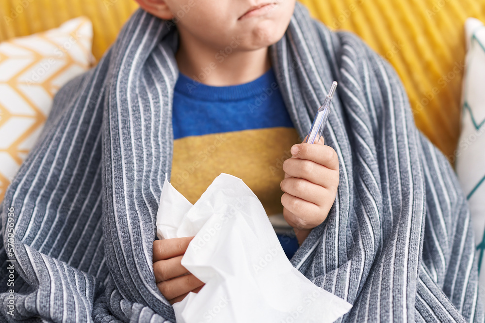 Canvas Prints Adorable hispanic boy holding napkin and thermometer sitting on sofa at home