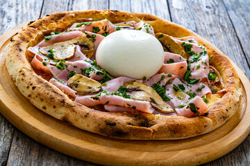 Circle prosciutto burrata pizza with mushrooms on wooden table