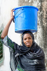Afro beauty carrying a bucket of water on her head