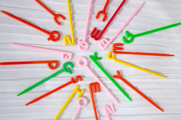 Colorful plastic sticks with English letters on top scattered on white. Word ok in the center. Fun educational toy for kids learning alphabet