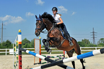 Girl riding a horse on jumping competitions.