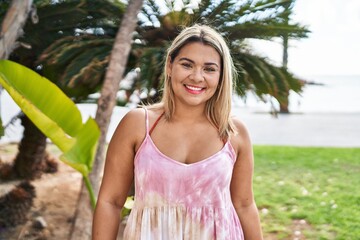 Young hispanic woman outdoors by the park looking positive and happy standing and smiling with a confident smile showing teeth