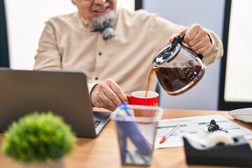 Middle age grey-haired man business worker pouring coffee on cup at office