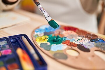 Middle age grey-haired man artist mixing color on palette at art studio