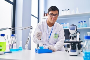 Down syndrome man wearing scientist uniform measuring liquid at laboratory