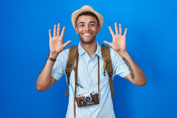 Naklejka premium Brazilian young man holding vintage camera showing and pointing up with fingers number ten while smiling confident and happy.