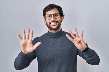 Naklejka premium Handsome latin man standing over isolated background showing and pointing up with fingers number nine while smiling confident and happy.