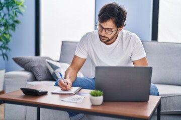 Fototapeta na wymiar Young hispanic man using laptop working at home