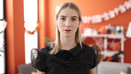 Young blonde woman wearing witch costume at home