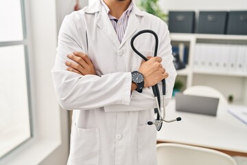 Young arab man wearing doctor uniform holding stethoscope at clinic