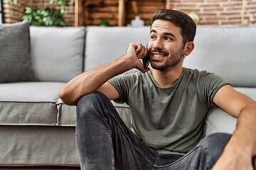 Young hispanic man smiling confident talking on the smartphone at home
