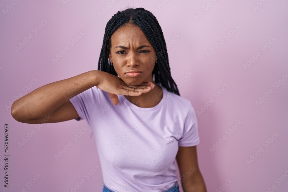 Poster african american woman with braids standing over pink background cutting throat with hand as knife, 