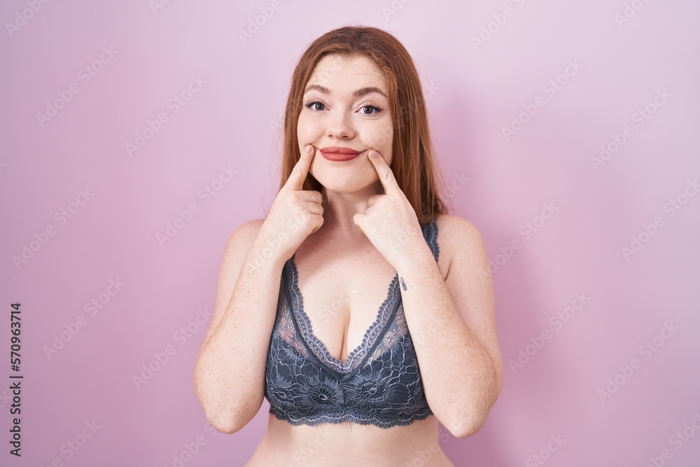 Canvas Prints redhead woman wearing lingerie over pink background smiling with open mouth, fingers pointing and fo