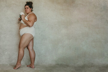 portrait of a plus size woman standing to the side holding flower looking forward