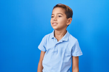 Little hispanic boy wearing casual blue t shirt looking to side, relax profile pose with natural...