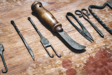 A selection of medieval surgical instruments on a blood-splattered wooden table