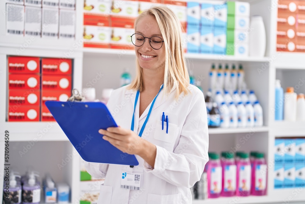 Canvas Prints Young blonde woman pharmacist writing on document at pharmacy