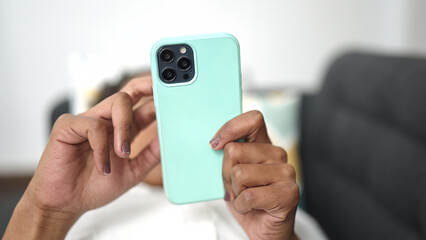 African american woman using smartphone lying on sofa at home