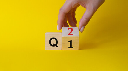 From 1st Quarter to 2nd symbol. Businessman hand Turnes cube and changes words 1st Quarter to 2nd Quarter. Beautiful yellow background. Business and Quarter concept. Copy space