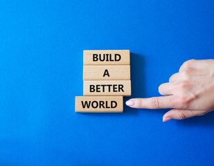 Build a better world symbol. Concept words Build a better world on wooden blocks. Businessman hand. Beautiful blue background. Business and Build a better world concept. Copy space.