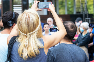 Citizen or mobile journalist filming and photographing media event or news conference with a...