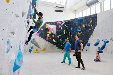 Men watching a friend climb in a bouldering gym