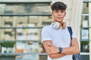 Young hispanic teenager student smiling confident standing with arms crossed gesture at university