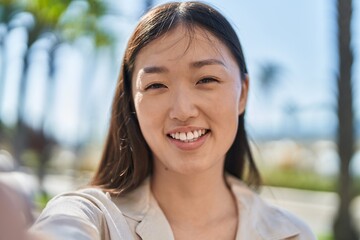 Chinese woman smiling confident making selfie by camera at street