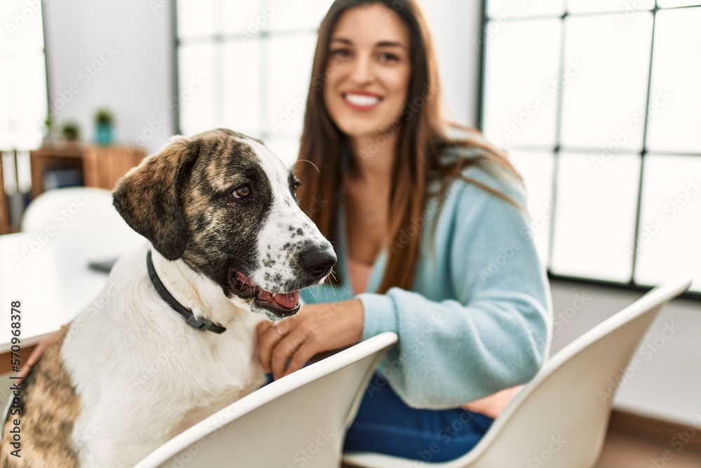 Sticker Young woman smiling confident sitting on table with dog at home