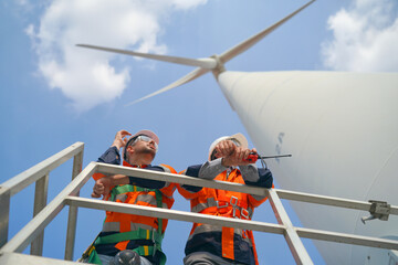 Wind turbine technicians working at the site work, low angle view on two engineers. © FotoArtist