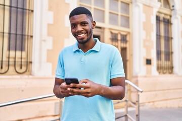 Young african american man smiling confident using smartphone at street