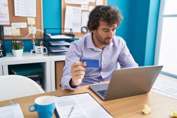 Young hispanic man business worker using laptop and credit card at office