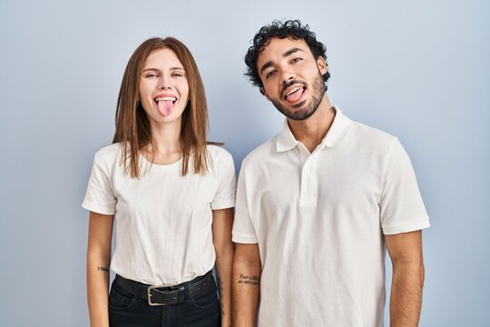Young couple wearing casual clothes standing together sticking tongue out happy with funny expression. emotion concept.
