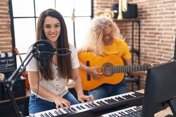 Fototapeta na wymiar Two women musicians singing song playing classical guitar and piano at music studio
