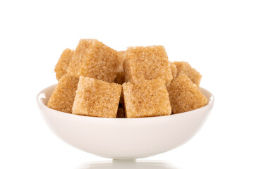 Several cubes of brown sugar in a white saucer, macro, isolated on a white background.